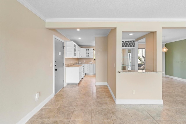 interior space with ornamental molding, light tile patterned flooring, white cabinetry, glass insert cabinets, and baseboards