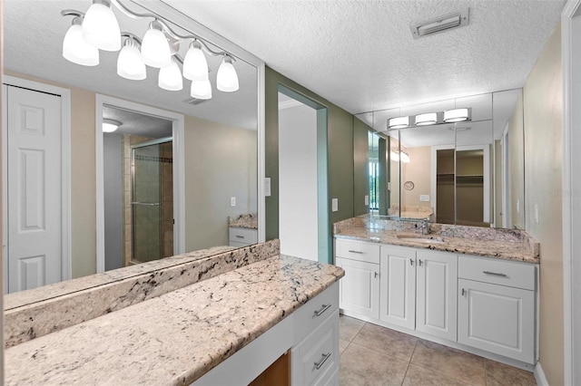 bathroom with vanity, a textured ceiling, a shower stall, and tile patterned flooring