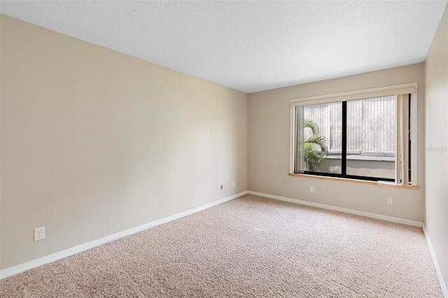 carpeted spare room with a textured ceiling and baseboards