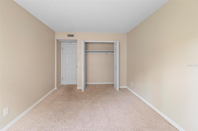 unfurnished bedroom with baseboards, light carpet, a closet, and visible vents