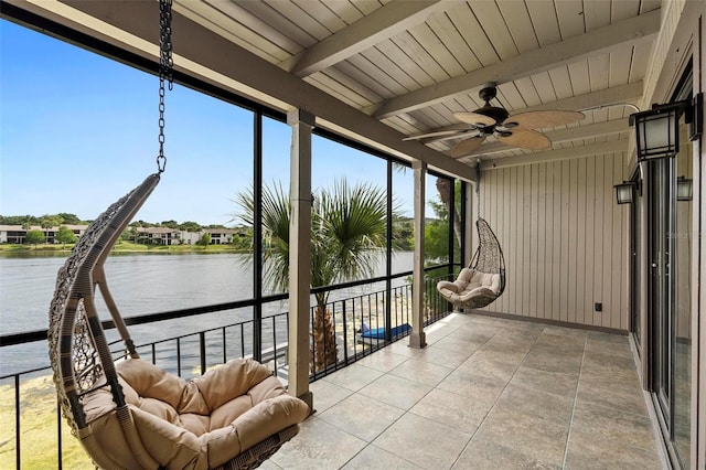 sunroom with beam ceiling, a water view, and ceiling fan