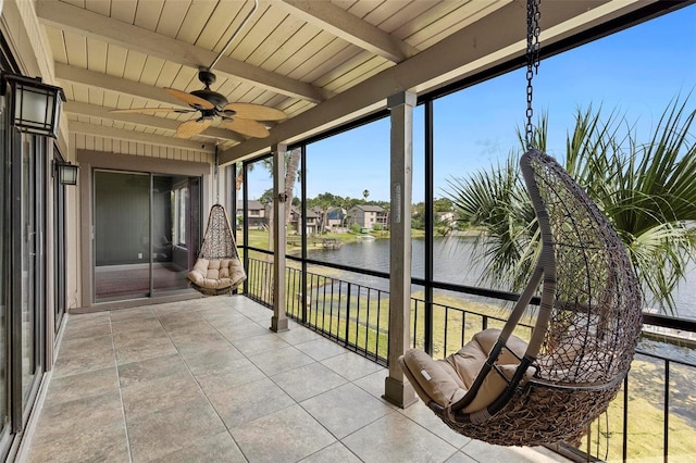unfurnished sunroom with beam ceiling, a water view, and a ceiling fan