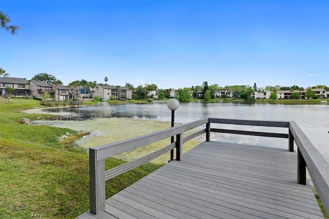 view of dock with a lawn, a water view, and a residential view