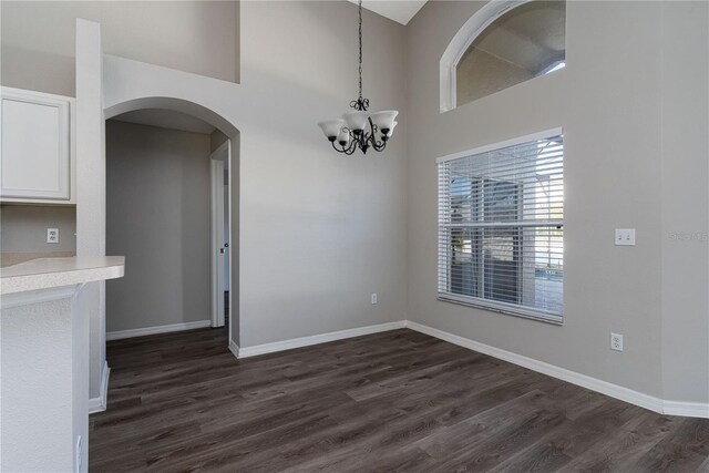 1175 Seasons Blvd, Kissimmee, FL 34746 - unfurnished dining area featuring dark wood-style flooring, baseboards, arched walkways, and a notable chandelier