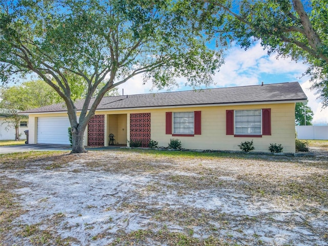single story home with an attached garage, concrete driveway, and fence