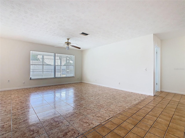 tiled empty room with ceiling fan, a textured ceiling, baseboards, and visible vents
