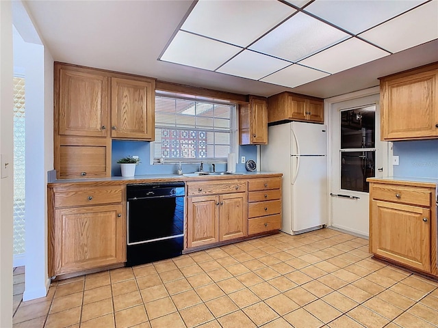 kitchen featuring light countertops, a sink, freestanding refrigerator, dishwasher, and light tile patterned flooring