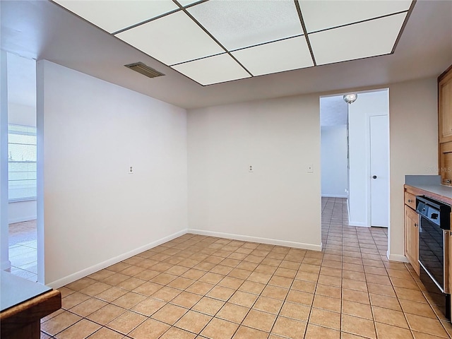spare room featuring baseboards, light tile patterned floors, and visible vents