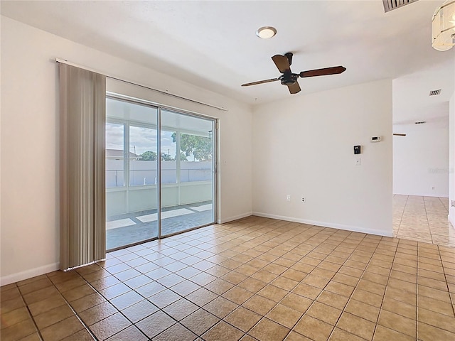 empty room with baseboards, ceiling fan, visible vents, and light tile patterned flooring