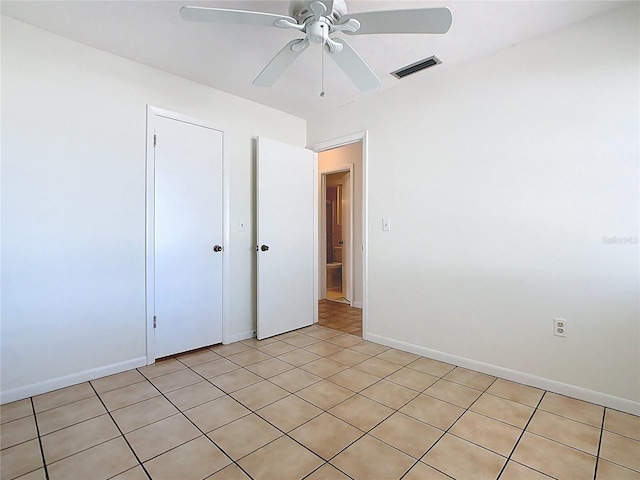 unfurnished bedroom featuring light tile patterned floors, a closet, visible vents, baseboards, and ceiling fan