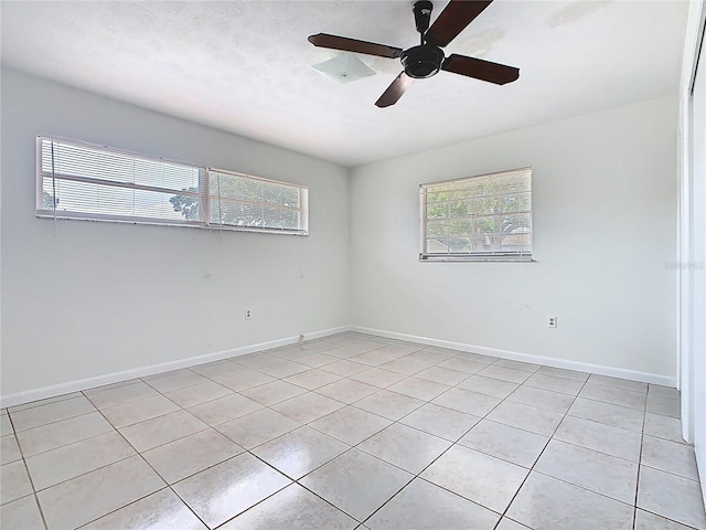 unfurnished room with light tile patterned floors, a healthy amount of sunlight, and a ceiling fan