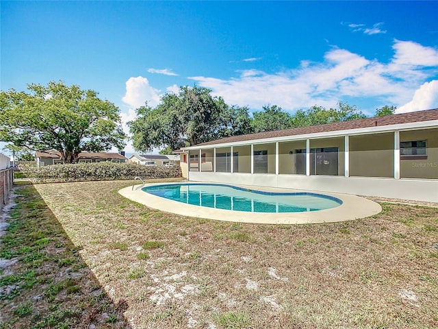 view of swimming pool featuring a sunroom, fence, a lawn, and a fenced in pool