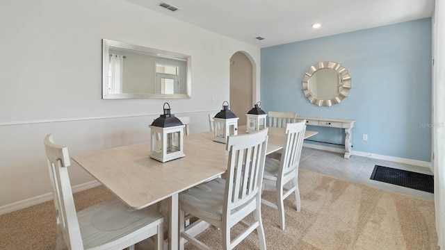 carpeted dining space featuring visible vents, tile patterned floors, recessed lighting, arched walkways, and baseboards