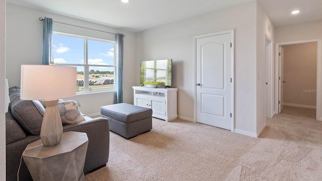sitting room with baseboards, recessed lighting, and light colored carpet