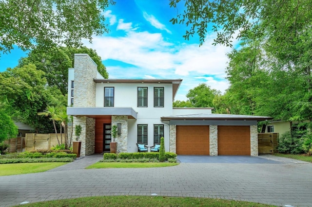 1831 Mizell Ave, Winter Park, FL 32789 - contemporary home with stone siding, stucco siding, an attached garage, decorative driveway, and fence