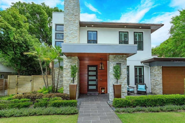 1831 Mizell Ave, Winter Park, FL 32789 - contemporary house featuring stone siding, fence, a balcony, stucco siding, and a porch