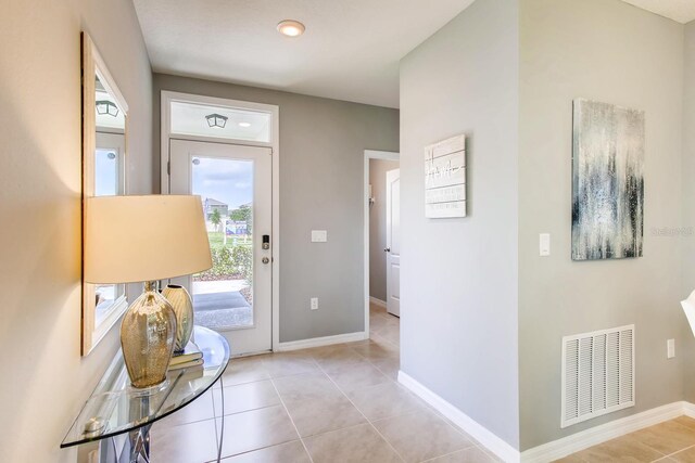 doorway featuring baseboards, light tile patterned floors, and visible vents