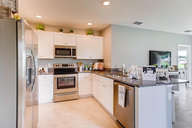 kitchen with a sink, a peninsula, visible vents, light tile patterned floors, and appliances with stainless steel finishes