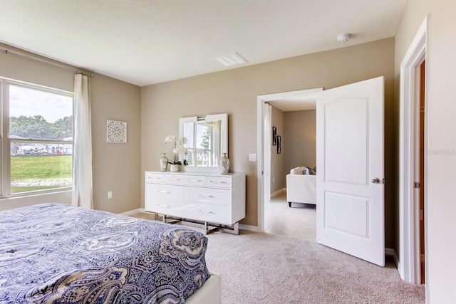 bedroom with baseboards, visible vents, and light colored carpet