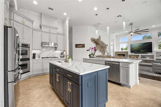 kitchen featuring stainless steel appliances, under cabinet range hood, crown molding, ceiling fan, and open floor plan