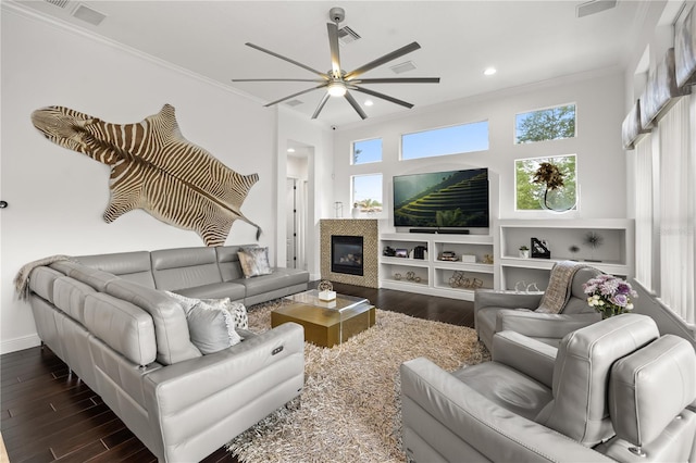 living room featuring crown molding, dark wood-style flooring, ceiling fan, a glass covered fireplace, and recessed lighting