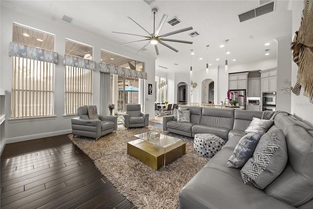 living area featuring visible vents, ceiling fan, and arched walkways