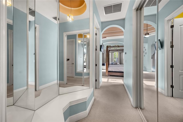 interior space featuring carpet floors, arched walkways, and visible vents