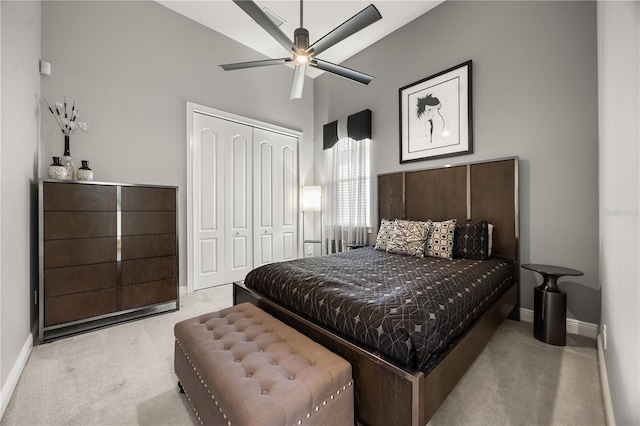 bedroom with baseboards, light carpet, a closet, and high vaulted ceiling