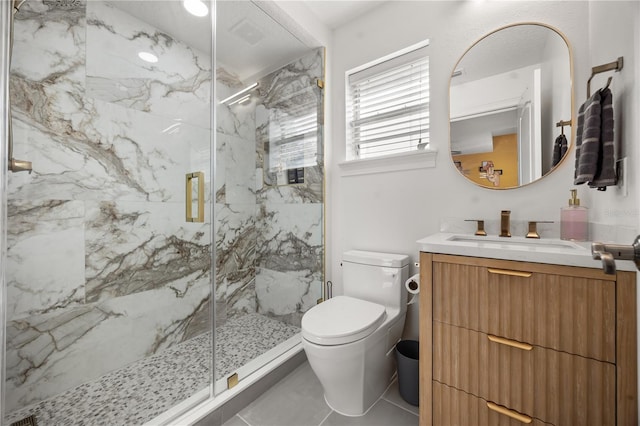 full bathroom featuring vanity, toilet, a marble finish shower, and tile patterned flooring