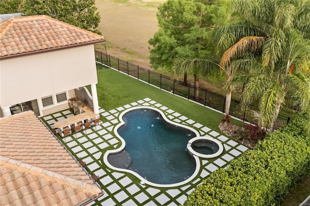 view of pool featuring a yard, a pool with connected hot tub, a fenced backyard, and a patio