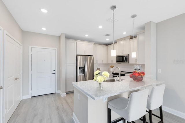 7565 Laureate Blvd Unit 3408, Orlando, FL 32827 - kitchen featuring appliances with stainless steel finishes, a peninsula, light wood-type flooring, a sink, and a breakfast bar