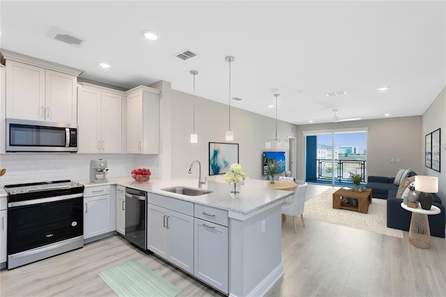 7565 Laureate Blvd Unit 3408, Orlando, FL 32827 - kitchen with stainless steel appliances, a sink, open floor plan, light wood finished floors, and a peninsula