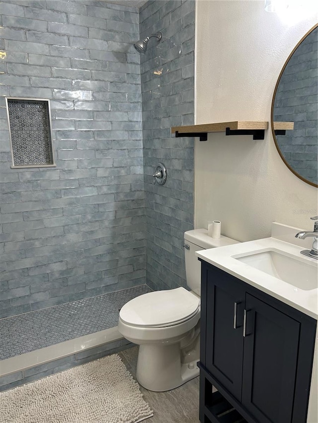bathroom featuring a tile shower, toilet, and vanity