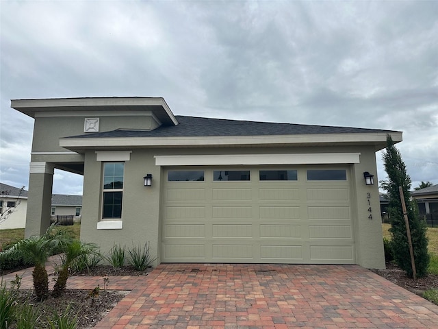 view of front of home with a garage, stucco siding, and decorative driveway