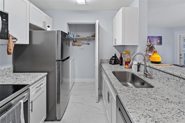 kitchen with white cabinets, marble finish floor, light stone countertops, and a sink
