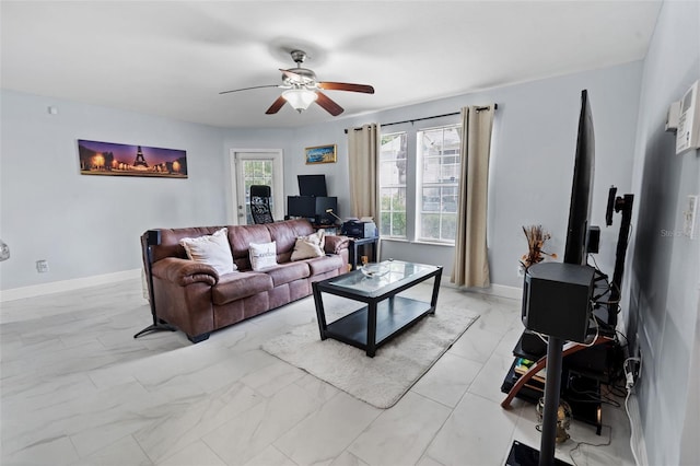 living area with baseboards, a ceiling fan, and marble finish floor