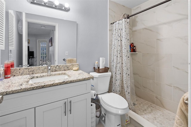 bathroom featuring a tile shower, vanity, and toilet