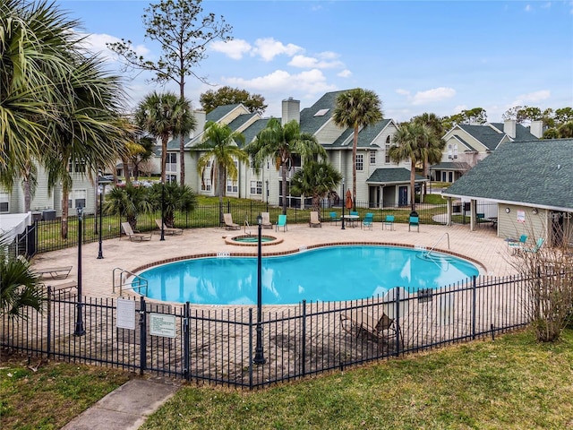 community pool featuring a patio area, a hot tub, fence, and a residential view