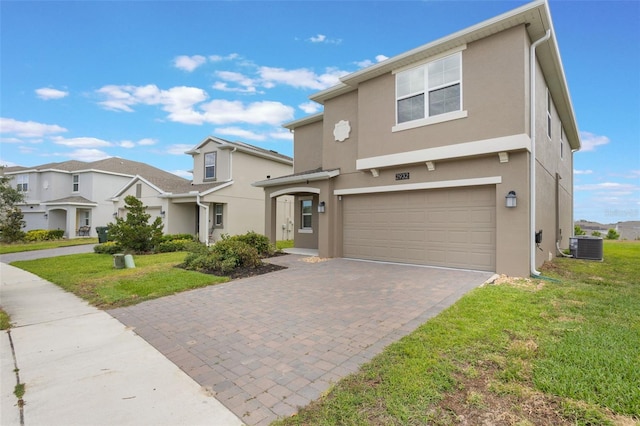 traditional-style home featuring a front lawn, stucco siding, decorative driveway, and a garage