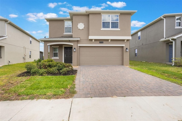 traditional-style house with a front yard, stucco siding, decorative driveway, and a garage