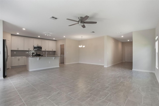 unfurnished living room featuring visible vents, baseboards, ceiling fan with notable chandelier, and recessed lighting