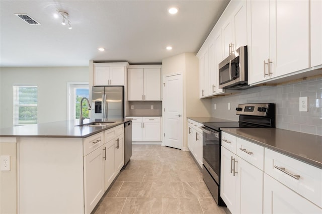 kitchen with appliances with stainless steel finishes, visible vents, tasteful backsplash, and a sink