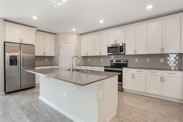 kitchen with a sink, stainless steel appliances, decorative backsplash, and an island with sink