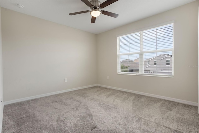 carpeted spare room featuring baseboards, a healthy amount of sunlight, and ceiling fan