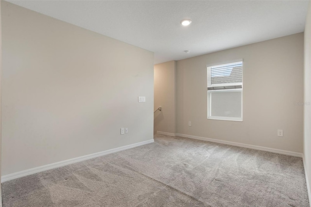 carpeted spare room featuring baseboards and recessed lighting