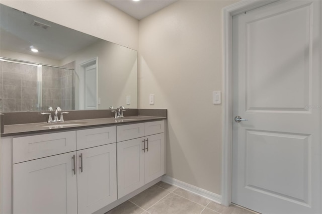 bathroom featuring a sink, visible vents, tile patterned floors, baseboards, and a tile shower