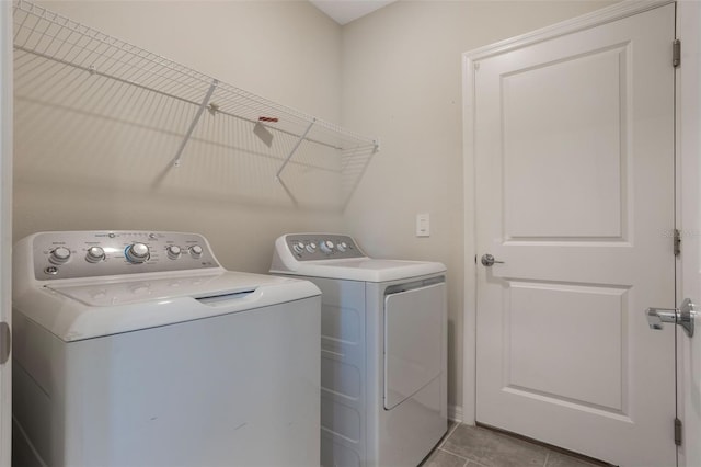 clothes washing area featuring light tile patterned floors, washing machine and dryer, and laundry area