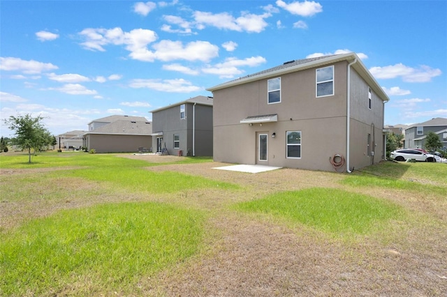 rear view of property with a yard, a patio, and stucco siding