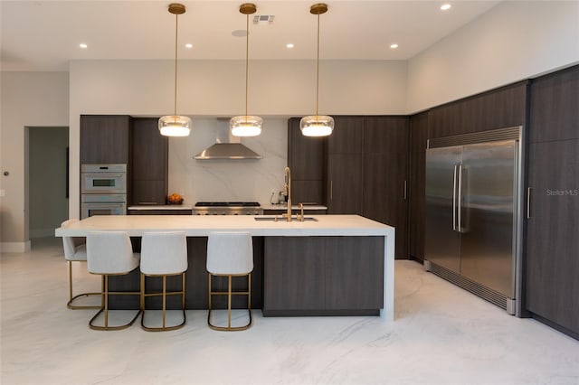 kitchen with a sink, wall chimney range hood, double oven, modern cabinets, and stainless steel built in fridge