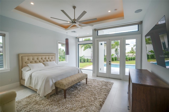 bedroom featuring french doors, a tray ceiling, visible vents, access to outside, and light tile patterned flooring